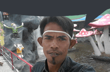 a man wearing a headband is standing in front of a waterfall and mushrooms