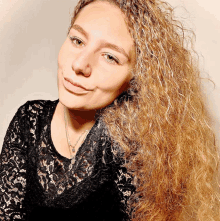 a woman with long curly hair is wearing a black lace top and necklace