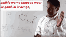 a man stands in front of a white board with a drawing of a chemical compound on it