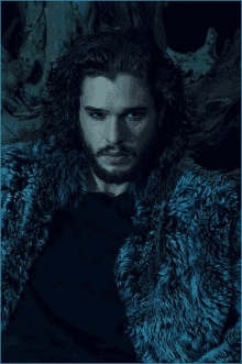 a man with long hair and blue eyes is wearing a blue fur coat