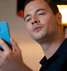 a man in a black shirt is looking at his cell phone