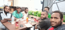 a group of men sit around a table with a bottle of coca cola