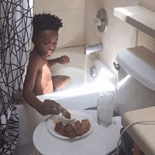 a young boy is taking a bath in a bathtub while eating chicken wings .