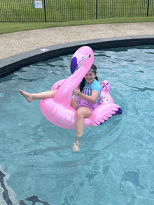 a girl sits on a pink flamingo float in a swimming pool