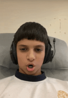 a young boy wearing headphones and a white shirt with a gold logo