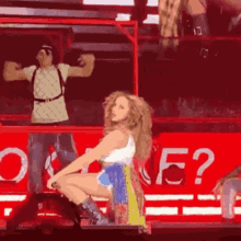 a woman is kneeling down on a stage in front of a red sign that says ' o ' on it