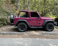 a pink jeep with bfgoodrich tires is parked on the side of the road