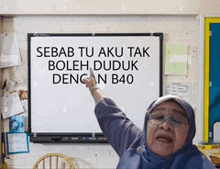 a woman is pointing at a white board that says sebab tu aku tak boleh duduk dengan b40