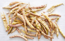 a pile of green beans in their pods on a wooden table .