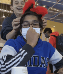 a boy wearing a blue adidas sweatshirt has a red headband on