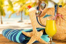 a straw bag sunglasses a starfish a towel and a drink on a table