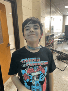 a boy wearing a black transformers t-shirt smiles for the camera