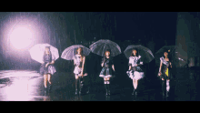 a group of girls standing in the rain holding clear umbrellas with one wearing a sash that says ' tokyo '