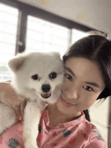 a woman holding a small white dog in her arms