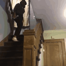 a man in a hat is walking down a set of stairs with a bottle in his hand