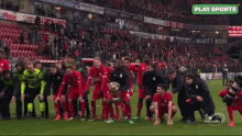 a group of soccer players are celebrating with a trophy in front of a crowd and a play sports logo