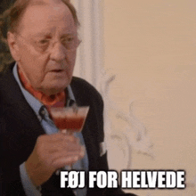 a man in a suit holds a wine glass and says " fej for helvede " on the bottom