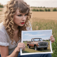 a woman is holding a picture of an old truck in a field