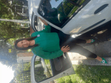 a woman in a green shirt is standing in front of a white car