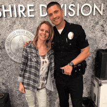 a man in a police uniform stands next to a woman in front of a sign that says shire division