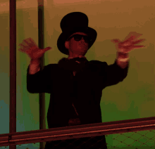 a man wearing a top hat and sunglasses is waving his arms