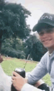 a man and a woman are sitting next to each other in a park drinking from a cup with a straw .