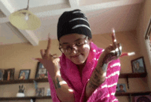 a girl wearing a pink sweater and a black beanie giving the middle finger