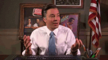 a man in a white shirt and tie is sitting at a desk in front of a coca cola sign