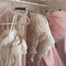 a bunch of pink and white clothes are hanging on a rack in a closet .