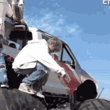 a man in a white hoodie is kneeling on a tire next to a vehicle that has the word jeep on the side