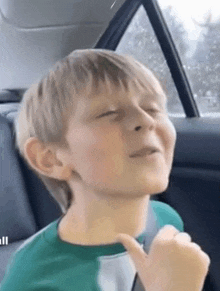 a young boy is sitting in the back seat of a car .