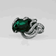 a silver ring with a green stone and a snake