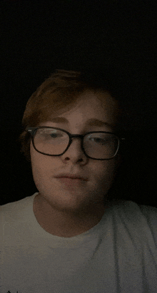 a young man wearing glasses and a white t-shirt