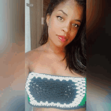 a woman wearing a crocheted crop top is taking a selfie