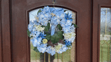 a wreath with blue and white flowers hangs on a brown door