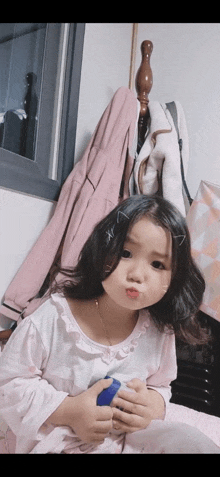 a little girl making a funny face while holding a blue object