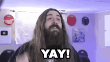 a man with long hair and a beard is saying yay !