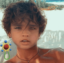 a young boy with curly hair looks at the camera with a baby rattle in front of him