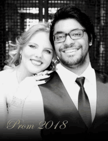 a black and white photo of a man and a woman posing for a prom picture .