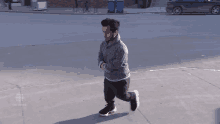 a man in a grey sweater and black pants is running on a sidewalk