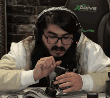 a man wearing headphones and glasses is working on a toy car with a xdrive chair in the background