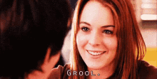 a woman with red hair is smiling at a man and the word grool is on the bottom of her face .