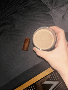 a hand holding a glass of coffee next to a piece of chocolate