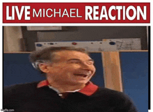 a man is laughing in front of a red sign that says `` live michael reaction '' .