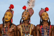 three men are standing next to each other with feathers on their head .