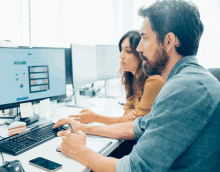 a man and a woman are looking at a computer screen together