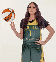 a woman in a seattle jersey holds a basketball in her hand