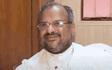 a man with glasses and a beard is smiling for the camera .