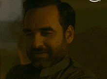 a man with a beard is smiling in a dark room with a white circle behind him