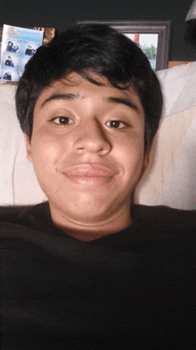 a young man laying on a couch with a framed picture of a boy behind him